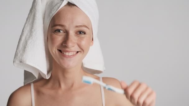 Close up beautiful girl with towel on head joyfully dancing with toothbrush isolated. Happy expression - Footage, Video