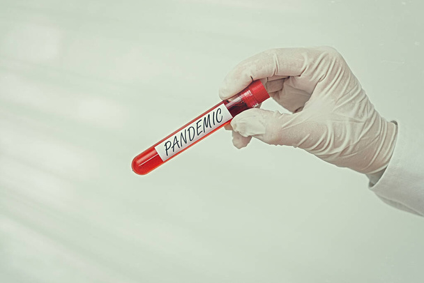 Writing note showing Pandemic. Business photo showcasing occurring over a wide area affecting high proportion of population Extracted blood sample vial ready for medical diagnostic examination . - Photo, Image