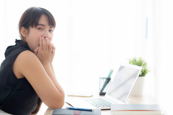 Güzel, genç, serbest çalışan Asyalı kadın ofisteki dizüstü bilgisayarda sıkılmış ve yorgun kız uykulu ve defterde esniyor tükenmiş iş konsepti olan kadın sekreter.. - Fotoğraf, Görsel