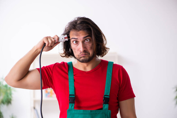 Divertente giovane elettricista maschio che lavora in casa - Foto, immagini