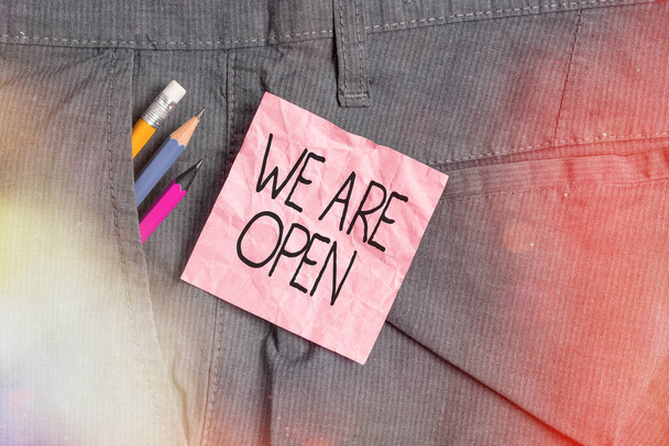Textzeichen mit der Aufschrift We Are Open. Konzeptfoto ohne umschließende oder einschließende Barriere, allseitig zugänglich Schreibgeräte und rosafarbenes Notizpapier in der Arbeitshosentasche. - Foto, Bild