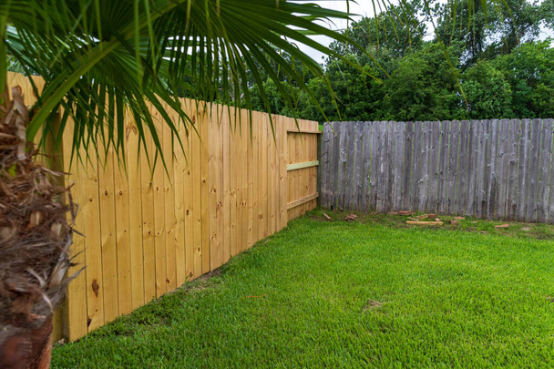 Nieuwe en oude privacy houten hekken in de achtertuin. - Foto, afbeelding
