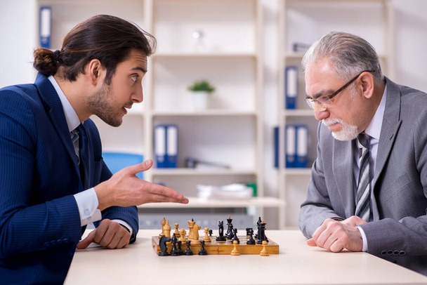 Два бизнесмена играют в шахматы в офисе - Фото, изображение