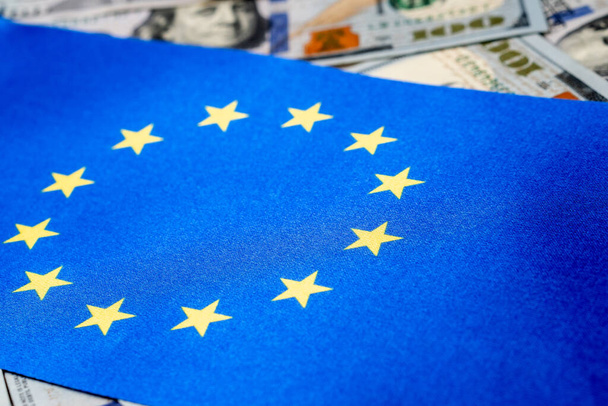 Bandera de la Unión Europea con dólares estadounidenses como fondo. Concepto para inversores, enfoque suave
 - Foto, imagen