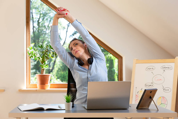 Beautiful women performing exercises and stretching in front of a laptop. Working at home, health concept. - Foto, Imagen