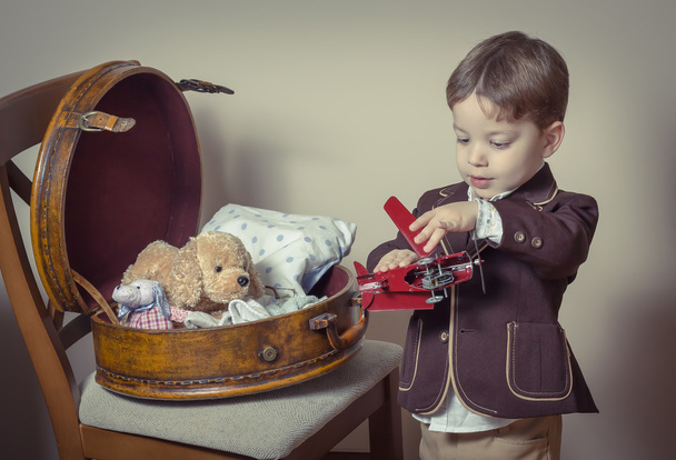 Винтажный портрет мальчика, играющего с жестяными игрушками
 - Фото, изображение
