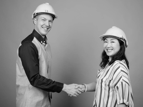 Jeune homme d'affaires et femme d'affaires japonaise mature ensemble sur fond gris en noir et blanc - Photo, image