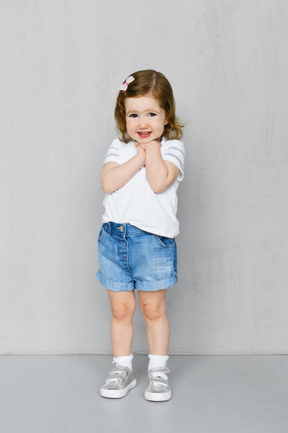 Two years old girl in white t-short and jeans shorts posing in studio - Fotografie, Obrázek