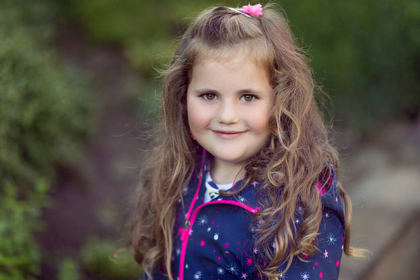 Kıvırcık sarı saçlı mutlu küçük kızın yakın plan portresi. - Fotoğraf, Görsel