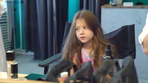 little girl hair stylist making curls on long hair in dressing room - Felvétel, videó