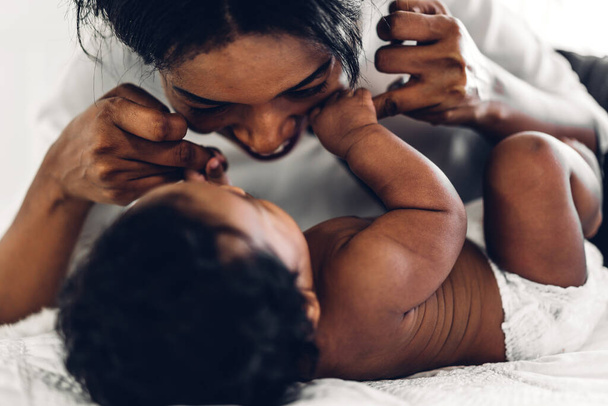 Portrait of enjoy happy love family african american mother playing with adorable little african american baby.Mom touching with cute son moments good time in a white bedroom.Love of black family concept - Foto, imagen