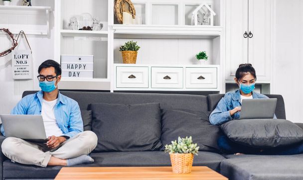 Fiatal ázsiai pár használ laptop számítógép munka és videó konferencia találkozó online chat karanténban a koronavírus visel védő maszk a társadalmi távolság otthon.work otthonról koncepció - Fotó, kép