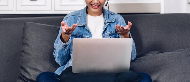 Jeune souriant heureux belle femme asiatique détente en utilisant ordinateur portable travail et vidéo conférence réunion à la maison.Jeune fille créative parler avec headset.work concept de la maison - Photo, image