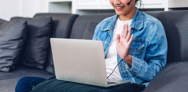 Junge lächelnd glücklich schöne asiatische Frau entspannen mit Laptop Computer arbeiten und Videokonferenz-Meeting zu Hause. Junge kreative Mädchen sprechen mit headset.work von zu Hause aus Konzept - Foto, Bild