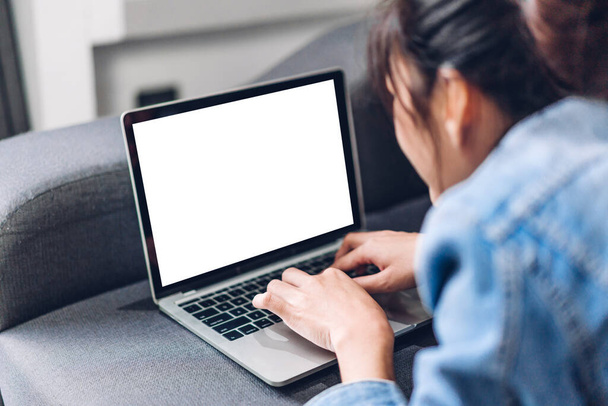 Jeune femme créative se détendre en utilisant un ordinateur portable de travail et dactylographier sur le clavier avec des écrans blancs maquette blanche à la maison - Photo, image