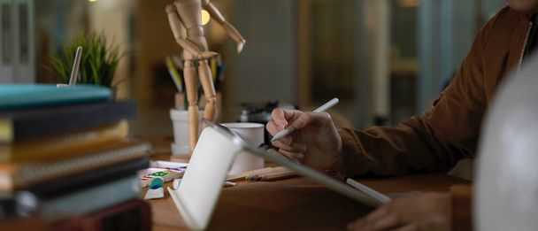 Side view of female college student doet opdracht met digitale tablet, boeken en benodigdheden op houten tafel - Foto, afbeelding
