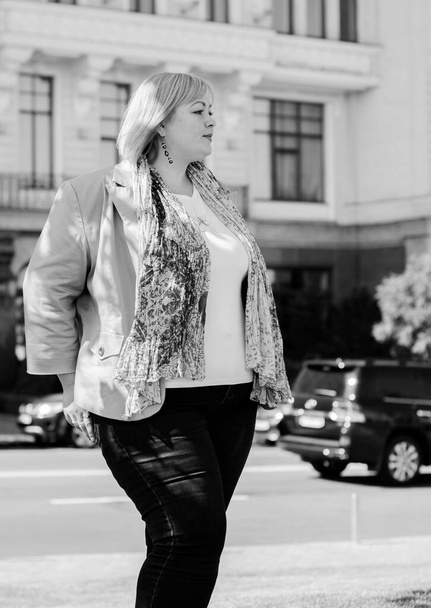 Feliz mujer con sobrepeso caminando por la calle de la ciudad en buen día. Soleado retrato de tamaño más dama. Mujer hermosa con sobrepeso de pie en la calle de la ciudad
 - Foto, Imagen