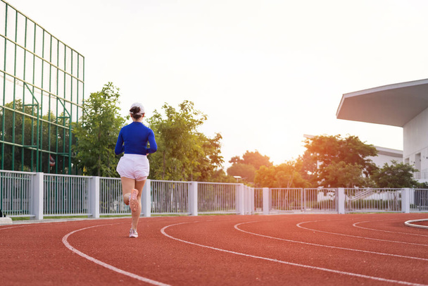 Jonge fitnessvrouw hardloper joggen oefening in de ochtend op Stadsstadion track in de stad. Vrouwelijke atleet oefening in het stadion van de stad om lichaam fitness te houden. Gezondheid en recreatie stock foto. - Foto, afbeelding