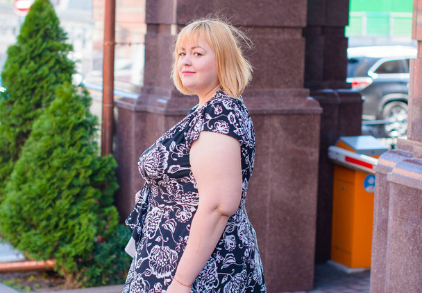 Šťastná žena s nadváhou, která se prochází po ulici v dobrý den. Slunečný portrét velikosti plus dáma. Krásná nadváha žena stojící na ulici - Fotografie, Obrázek