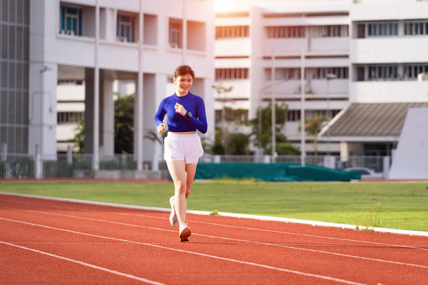 Young fitness woman runner jogging excercise in the morning on city stadium track in the city. Female athlete excercise in the city stadium to keep body fitness. Health and recreation stock photo. - Photo, Image