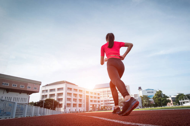 Genç fitness kadın koşucusu sabah şehir stadyumundaki pistte egzersiz yapıyor. Vücut sağlığını korumak için stadyumda kadın sporcu egzersizi. Sağlık ve Rekreasyon Stoku fotoğrafı. - Fotoğraf, Görsel