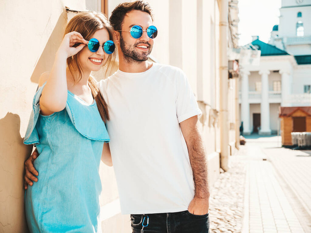 Portrait of smiling beautiful girl and her handsome boyfriend.Woman in casual summer jeans dress.Happy cheerful family.Female having fun.Couple posing on the street background in sunglasses - Фото, изображение