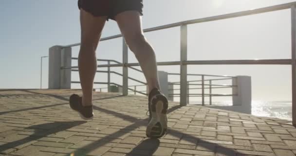Senior fit Caucasian man working out on promenade by the sea wearing sports clothes, running on a sunny day in slow motion. Retirement healthy lifestyle activity. - Video