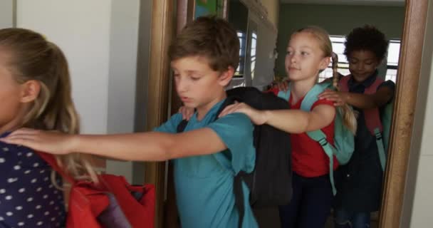 Multi-ethnic group of children walking single file with hands on each others shoulders along an outside corridor between classrooms, in slow motion. education at an elementary school. - Filmagem, Vídeo