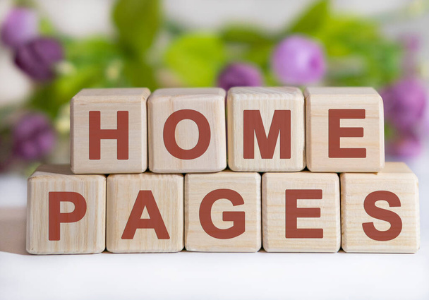 Home pages - concept on wooden cubes on a white table with flowers in the background - Photo, Image
