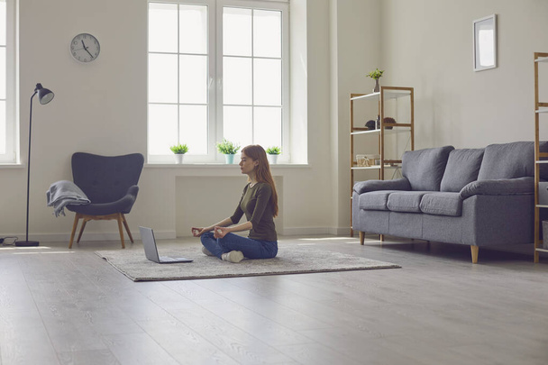 Yoga meditation online. Woman with laptop sitting in Lotus pose on rug indoors - Fotografie, Obrázek