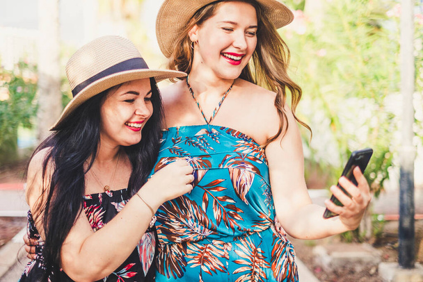 Pari nuorta naispuolista ystävää nauttivat ulkoilmasta yhdessä nykyaikaisen yhteyden ja älypuhelimen avulla kommunikoidakseen ja pitääkseen hauskaa yhdessä - Valokuva, kuva