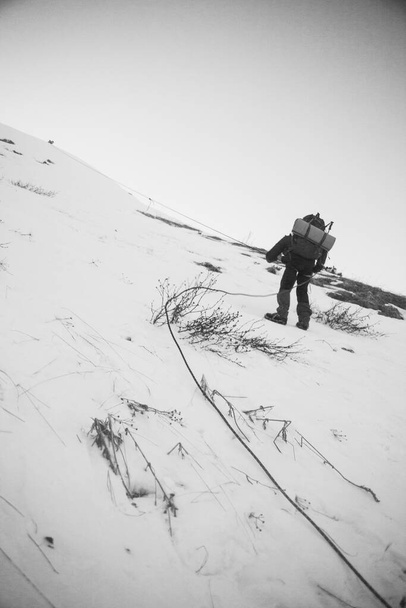 Alpinista en las montañas, rollover. Paisaje de invierno blanco y negro con silueta
 - Foto, Imagen