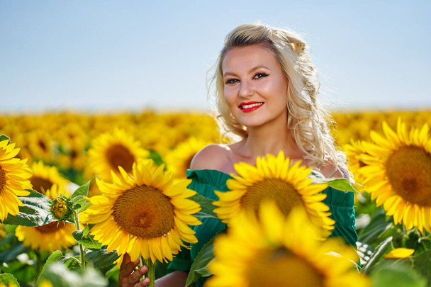 Attractive young woman in a sunflowers field mid summer - Foto, Imagen