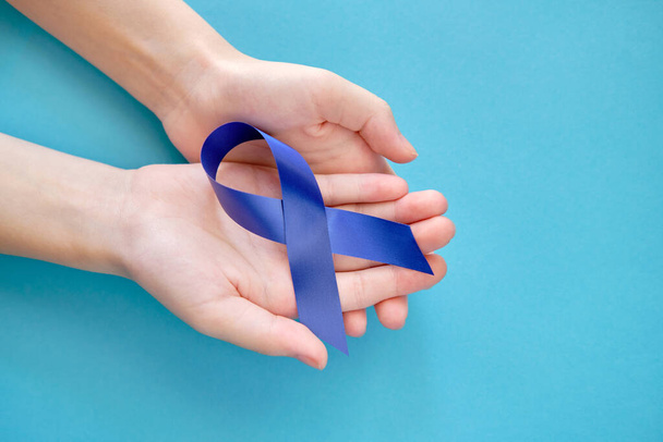 Blue ribbon on on two hands is a symbol of the problem of Stevens-Jones syndrome, colon cancer, problem of hydranencephaly, chronic fatigue syndrome, myalgic encephalomyelitis - Fotografie, Obrázek