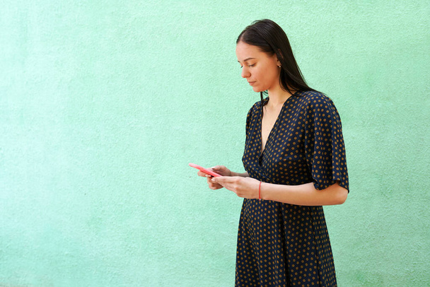 portré gyönyörű fiatal nő kezében okos telefon zöld háttér másolási hely - Fotó, kép