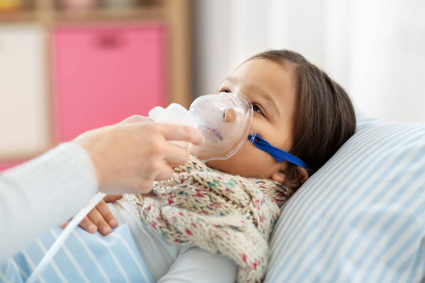 mother and sick daughter with oxygen mask in bed - Photo, Image