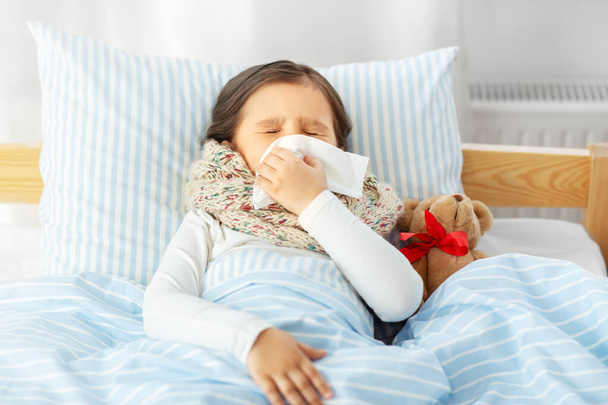 sick girl lying in bed and blowing nose at home - Φωτογραφία, εικόνα
