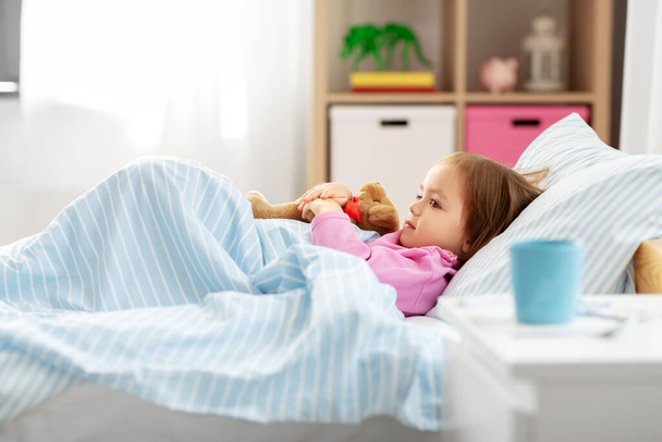 sick little girl lying in bed at home - Foto, Imagem