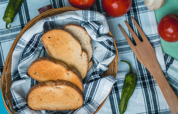 Βιολογικές και φρέσκες ντομάτες πράσινες πιπεριές, ζυμαρικά και σκόρδο με φρυγανισμένο ψωμί στο καλάθι Ιταλικά τρόφιμα μπαχαρικά ξερή ρίγανη ξύλο πιρούνι - Φωτογραφία, εικόνα