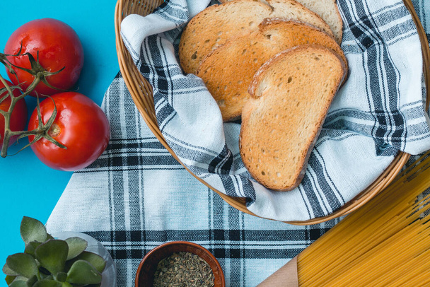 Pane tostato in cesto e pomodori freschi sulla tavola di stoffa, pasta spaghetti e spezie cibo italiano - Foto, immagini
