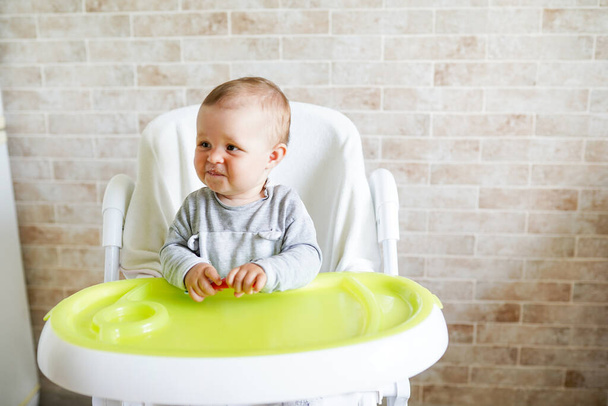 bebé sentado en silla en la cocina soleada. Nutrición saludable para los niños. espacio de copia - Foto, imagen