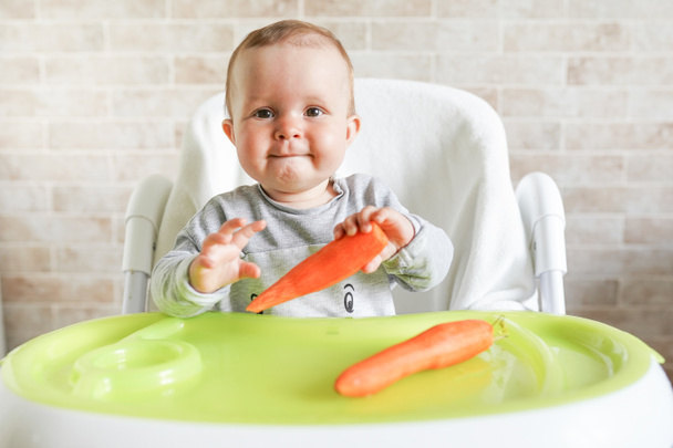 Bebé come verduras. Primer alimento sólido para un niño pequeño. Zanahoria orgánica fresca para el almuerzo vegetal. Nutrición saludable para los niños
 - Foto, Imagen