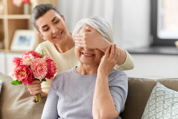 adult daughter giving flowers to old mother - Foto, Imagen