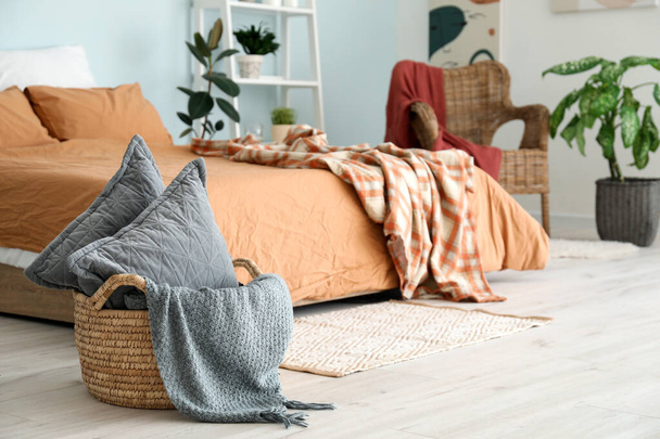 Elegante interior de dormitorio con almohadas en cesta
 - Foto, imagen