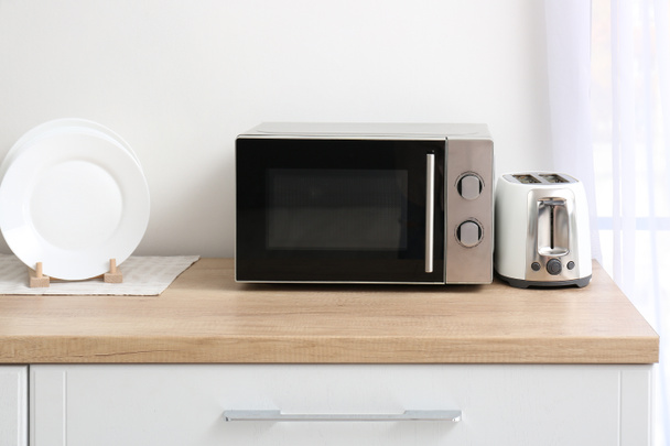 Mutfak masasında tost makinesi olan mikrodalga fırın. - Fotoğraf, Görsel