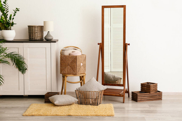Gran espejo, cómoda con silla, cestas y almohadas en la habitación
 - Foto, Imagen