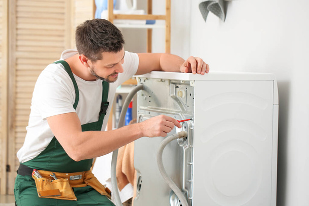 Arbeiter repariert Waschmaschine in Waschküche - Foto, Bild