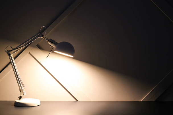 Svítící lampa na stole v tmavé místnosti - Fotografie, Obrázek