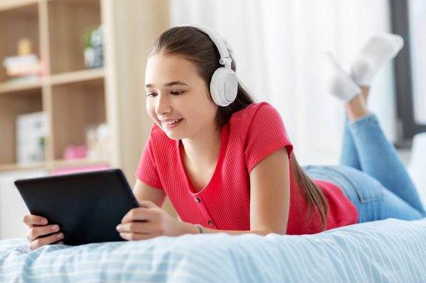 girl in headphones listening to music on tablet pc - Fotó, kép