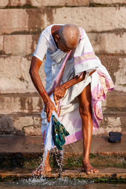 Стара пані в білому, що пере одяг у Ганг Рівер. Варанасі (Індія)  - Фото, зображення